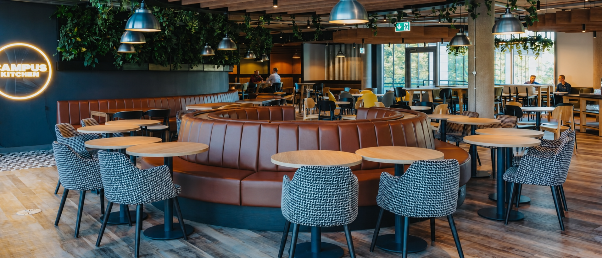 Commercial dining interior with curved upholstered seating, tables and loose chairs